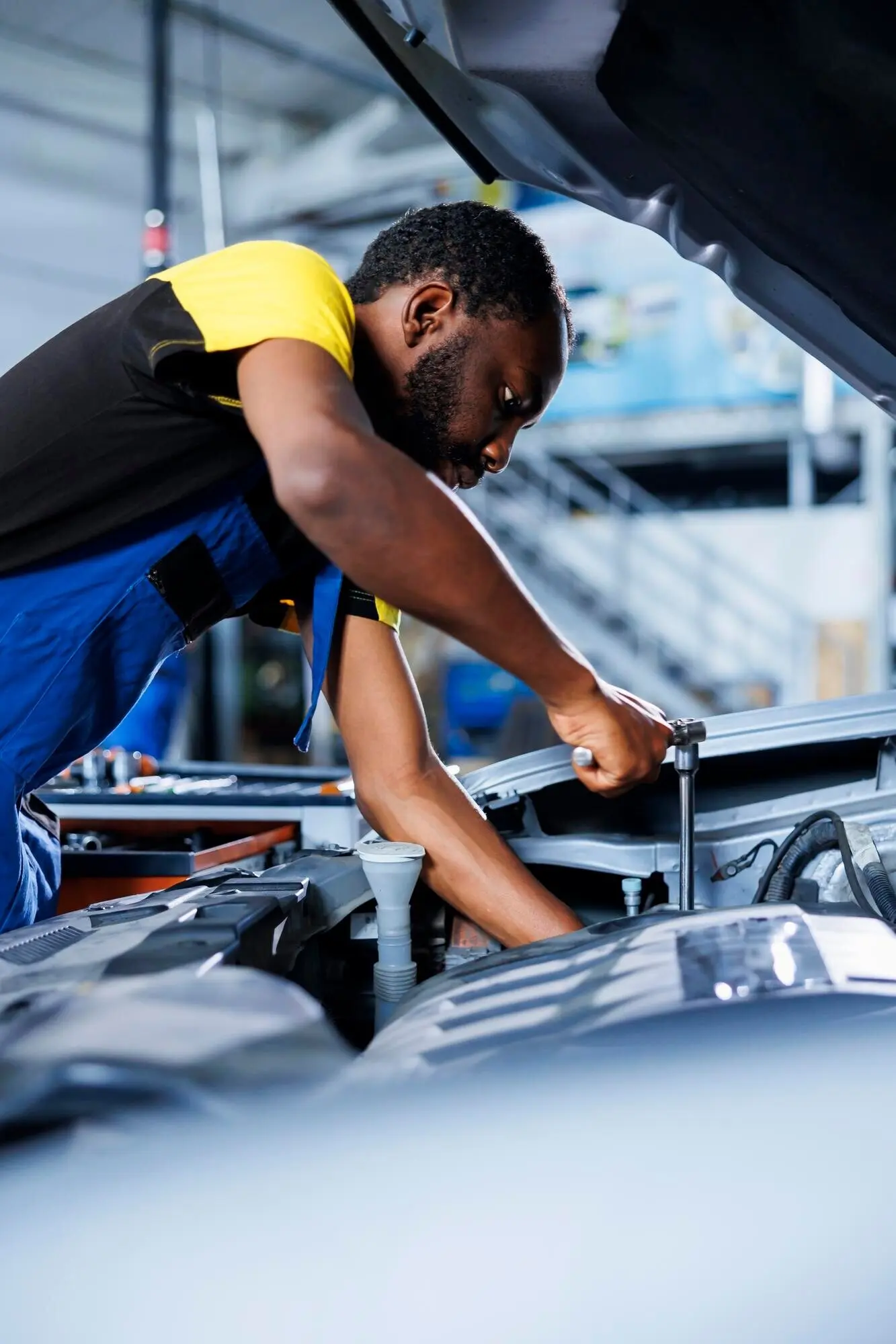 A proficient mechanic at a car service garage uses a professional mechanical tool to repair a broken fuel tank, fixing a client's automobile and ensuring optimal automotive performance.