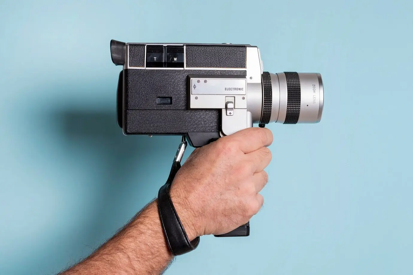 Close-up view of a man's hand holding against a blue background.